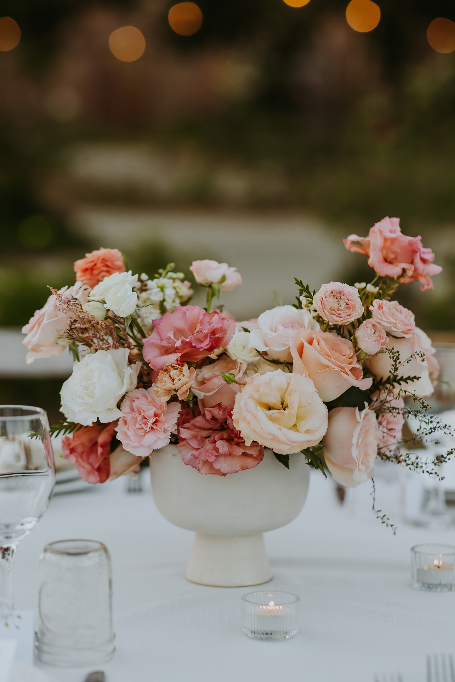 Soft pink and peach floral centerpiece in a white vase, ideal for elegant Los Cabos flower delivery and intimate gatherings. Del Mar Floristería.
